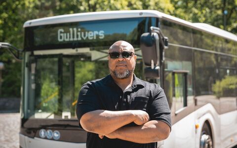 Sportlich, kräftiger Busfahrer steht vor seinem Linienbus